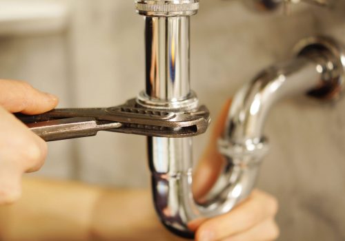 Plumbing repair service. Professional installer with spanner checking pipe.